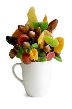 Beyaz arka planda, bir buket kurutulmuş meyve ve fındık ile el yapımı bir kupa var. .