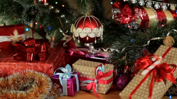 Червоний різдвяний м'яч на ялинку, свічки та подарунки — стокове відео