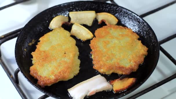 Matlagning potatis pannkakor i en stekpanna med bacon — Stockvideo