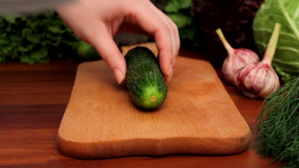 Dames handen snijden komkommer op een houten bord — Stockvideo