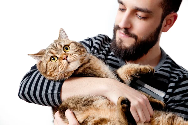 大胡子的年轻人拥抱他只漂亮的猫，在白色背景上 图库图片