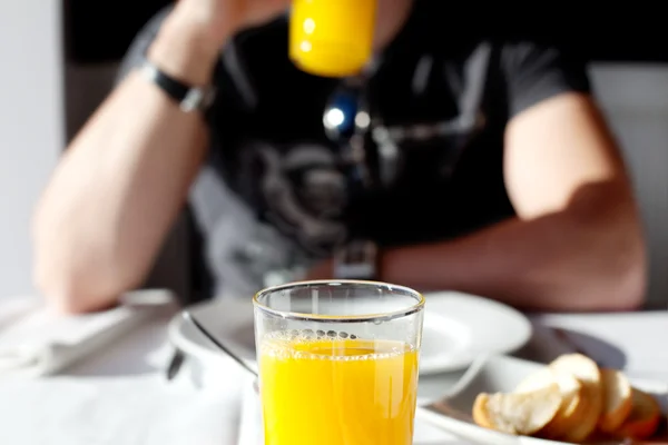 Chico tomando un vaso de jugo a la luz de una ventana — Foto de Stock