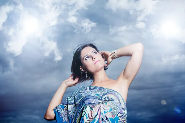 Beautiful young woman on a background of sky and clouds.Fashion