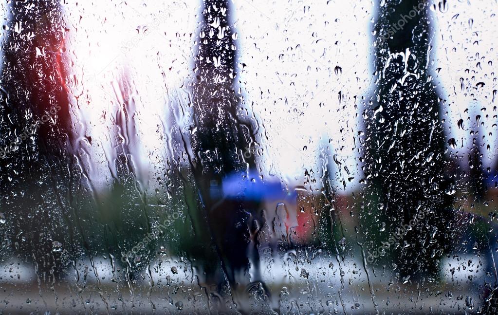 Abstract image of falling rain drops through the window with city background