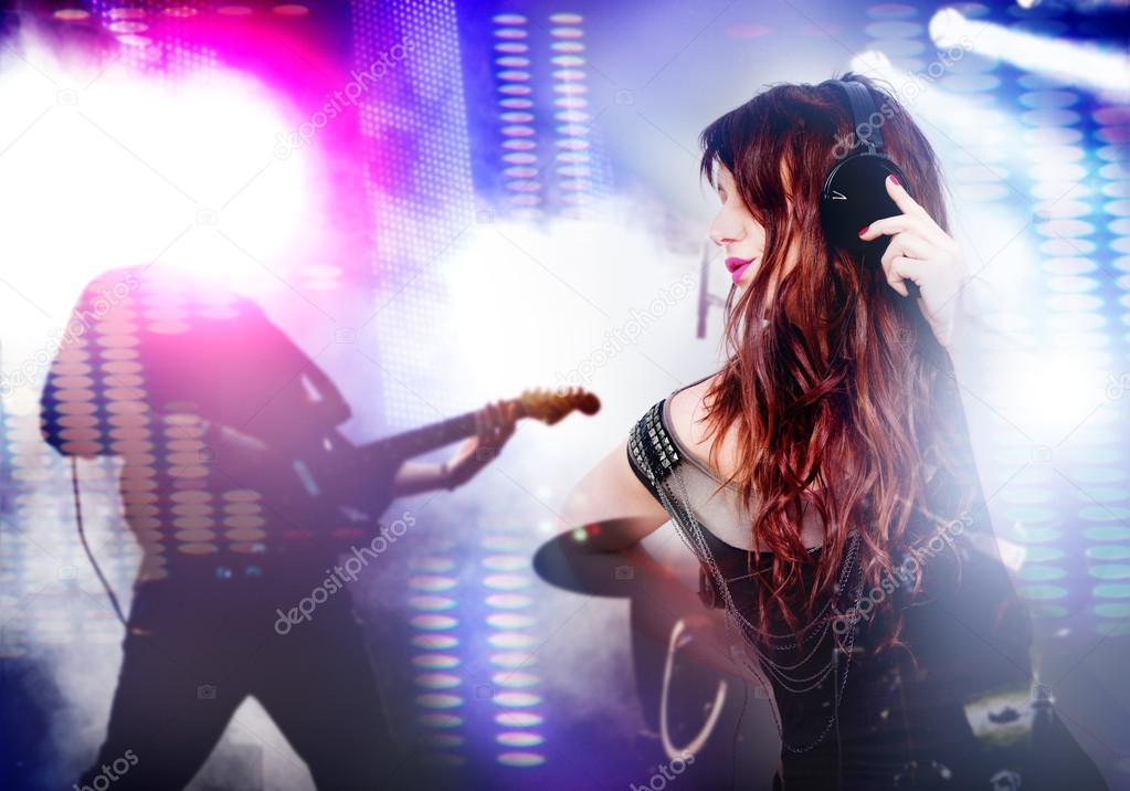 Beautiful woman listening to music with headphones. Live music background with guitar and bright lights on stage.