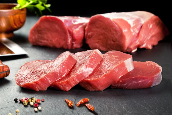 Fresh and raw meat. Sirloin medallions steaks in a row ready to cook. Background black blackboard — Stock Photo, Image