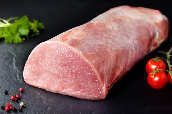 Carne crua e porco fresco. Fundo preto Rolo de carne suculenta de porco com tomate cereja ardósia — Fotografia de Stock