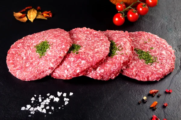 Çiğ et. Burger kasap ve siyah arka plan üzerine domates
