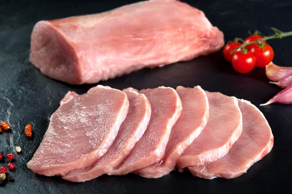 Carne fresca y cruda. Solomillo de cerdo, lomo medallones filetes en fila listo para cocinar. Pizarra negra fondo —  Fotos de Stock