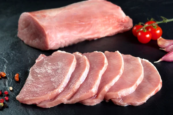 Vers en ruwe vlees. Varkenshaasje, loin medaillons Steaks in een rij klaar om te koken. Achtergrond zwarte schoolbord — Stockfoto