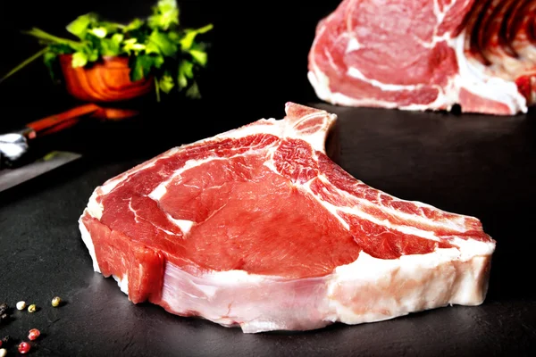 Carne fresca e cruda. Ribeye. Bistecche crude barbecue alla griglia su lavagna di sfondo nero. Carne alla griglia e barbecue, bistecche di carne cruda . — Foto Stock