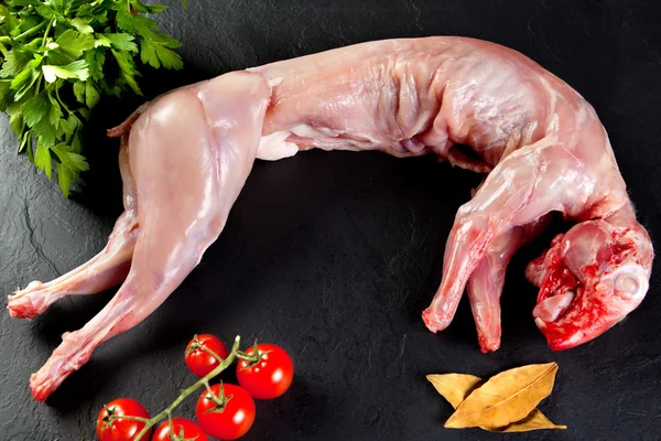 Carne cruda y fresca. Conejo entero listo para cocinar. Carniceros carne negro fondo . — Foto de Stock