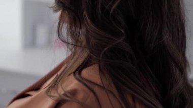 Kuaför, güzel bir kızın dikiz aynasındaki saç modelinin son aşamasını oluşturuyor. Profesyonel kuaför, sevimli Avrupalı küçük bir kız için saç stili yapıyor..