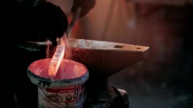 Demirci metalle çalışır. Demirci gemisi... demircinin elleri kızgın metali dövüyor ve her yöne kıvılcımlar saçıyor.