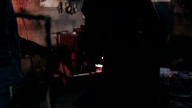 Demirci metalle çalışır. Demirci gemisi... demircinin elleri kızgın metali dövüyor ve her yöne kıvılcımlar saçıyor.