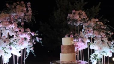  Düğün pastası kemerin arkasında dekorlu.