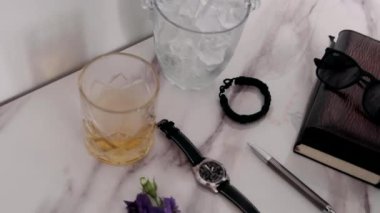Erkek elleri bardağa alkolle buz koyar.