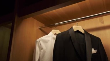 Adamın takım elbisesi dolapta asılı ve aydınlanmış. Terzide erkek kıyafeti. Erkeklerin elleri gardıroplarından bir ceket seçer. Erkek seçimi