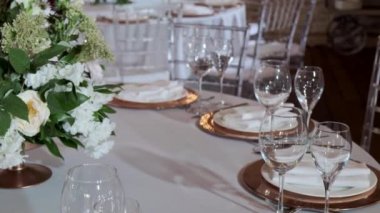 Restoranda, masalar masa örtüleriyle kaplı, altın tabaklar ve parlak bardaklarla servis ediliyor..