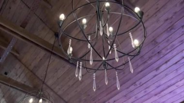 Ahşap bir binanın tavanında asılı mum şeklinde bir avize.