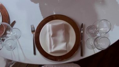 Restoranda, masalar masa örtüleriyle kaplı, altın tabaklar ve parlak bardaklarla servis ediliyor..