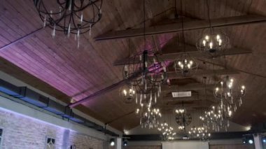 Ahşap bir binanın tavanında asılı mum şeklinde bir avize.