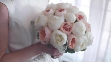 Düğün buketi dolusu taze beyaz Peonie. Düğün takıları peçe ile örtülü kadın ayakkabılarının yanında. Ayakkabılar cama yansıyor. metin eklenecek bir yer var