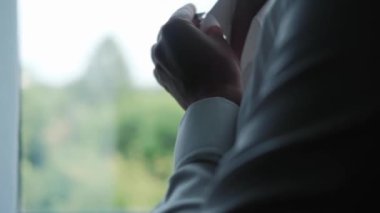 Adam otel odasında takım elbise giyiyor.