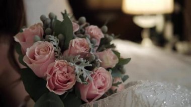 Gelin elinde bir buket beyaz gül tutuyor.