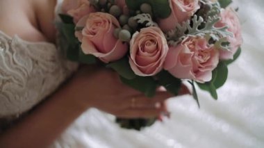 Gelin elinde bir buket beyaz gül tutuyor.