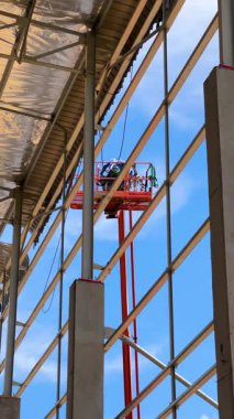 Bir vinç işçileri inşaat halindeki bir binanın çatısına çıkarıyor.