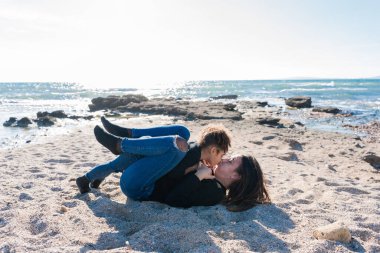 Genç bir anne ve Afrikalı Amerikalı kızı arasında kumsalda sevgi dolu bir öpücük.