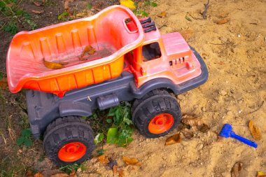 Kum havuzunda çocuk oyuncakları. Plastik oyuncak kamyonu kumun üzerinde.