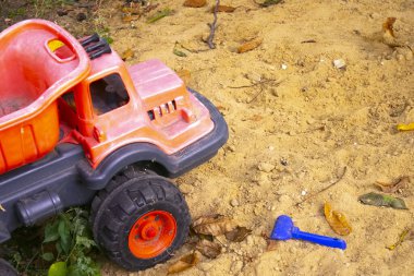 Kum havuzunda çocuk oyuncakları. Plastik oyuncak kamyonu kumun üzerinde.