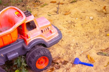 Kum havuzunda çocuk oyuncakları. Plastik oyuncak kamyonu kumun üzerinde.