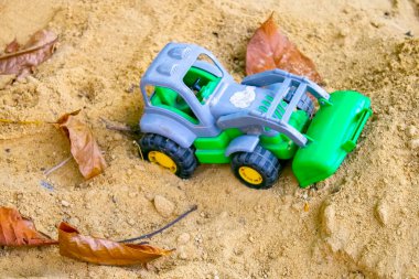 Kum havuzunda çocuk oyuncakları. Plastik oyuncak kamyonu kumun üzerinde.