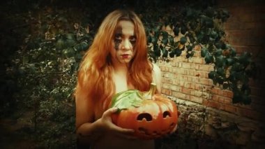 Genç seksi cadı elinde oyulmuş bir balkabağı, cadılar bayramı geçmişi