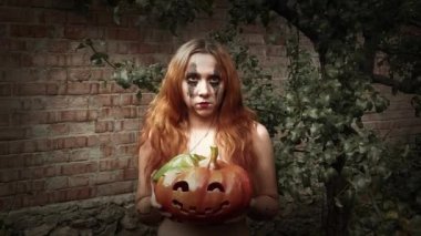 Genç seksi cadı elinde oyulmuş bir balkabağı, cadılar bayramı geçmişi