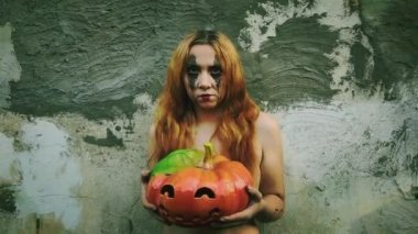 Genç seksi cadı elinde oyulmuş bir balkabağı, cadılar bayramı geçmişi