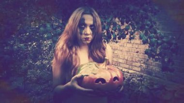 Genç seksi cadı elinde oyulmuş bir balkabağı, cadılar bayramı geçmişi