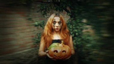 Genç seksi cadı elinde oyulmuş bir balkabağı, cadılar bayramı geçmişi