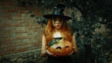 Genç seksi cadı elinde oyulmuş bir balkabağı, cadılar bayramı geçmişi