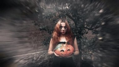 Genç seksi cadı elinde oyulmuş bir balkabağı, cadılar bayramı geçmişi