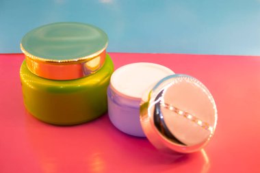 Pembe ve mavi arkaplanda farklı makyaj malzemeleri ve aksesuarları. Makyaj Moda Konsepti