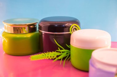 Pembe ve mavi arkaplanda farklı makyaj malzemeleri ve aksesuarları. Makyaj Moda Konsepti