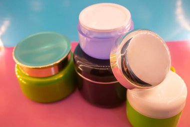 Pembe ve mavi arkaplanda farklı makyaj malzemeleri ve aksesuarları. Makyaj Moda Konsepti