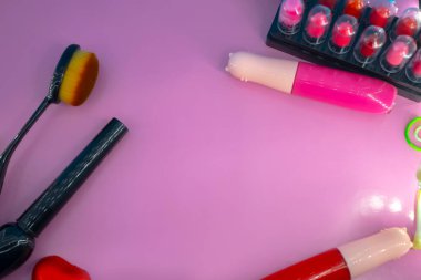 Pembe ve mavi arkaplanda farklı makyaj malzemeleri ve aksesuarları. Makyaj Moda Konsepti