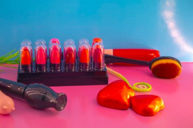 Pembe ve mavi arkaplanda farklı makyaj malzemeleri ve aksesuarları. Makyaj Moda Konsepti