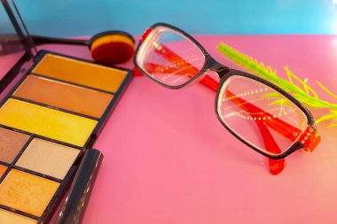 Pembe ve mavi arkaplanda farklı makyaj malzemeleri ve aksesuarları. Makyaj Moda Konsepti