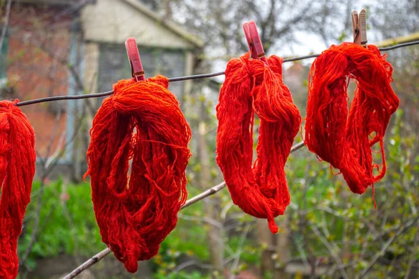 Woolen colorful threads are hanging on a clothesline with clothespins outdoor